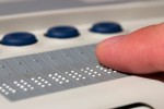 Una persona con disabilità visiva utilizza un display Braille, periferica di computer che permette di leggere attraverso il tatto, nel codice Braille, il contenuto della videata