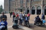 Alcuni tra i turisti italiani con disabilità che non hanno potuto visitare il Rijksmuseum di Amsterdam, fotografati di fronte alla struttura della capitale olandese (foto di Emanuele Piunti)