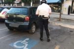 Un agente di Polizia Locale sanziona un autoveicolo parcheggiato abusivamente in un posto riservato a persone con disabilità