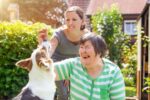 Una caregiver familiare insieme a una propria congiunta con disabilità e a un amico a quattro zampe