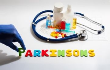 Farmaci, mano guantata, stetoscopio e la scritta Parkinsons