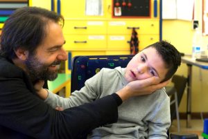 L'attore Neri Marcorè, testimonial della Lega del Filo d'Oro, accarezza un bambino con pluridisabilità psicosensoriale