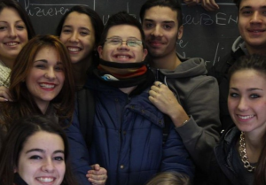 Un ragazzo con sindrome di Down insieme a compagni e compagne di scuola