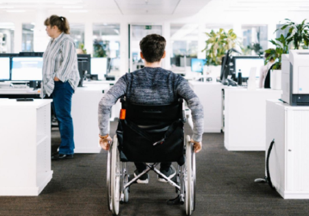 Giovane con disabilità in carrozzina in un luogo di lavoro