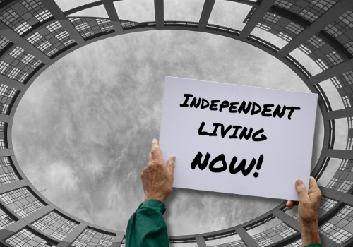 Mani reggono un cartello con la scritta "Independent Living Now!"
