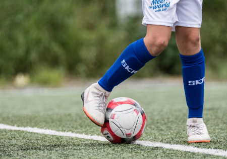 Gambe di giovane calciatore con il pallone