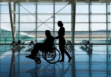 Ombra di persona in carrozzina in aeroporto, spinta da una donna