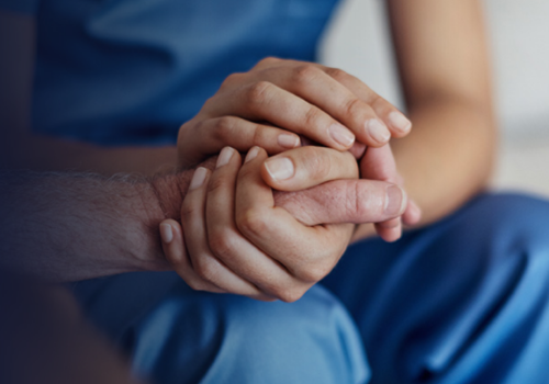 Mano di operatore sanitario che stringe la mano di un paziente