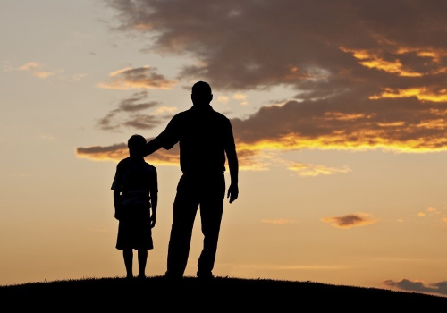 Ombre di adulto e ragazzo davanti a un tramonto