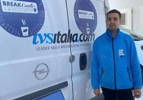 Giulio al lavoro, vicino a un furgone dell’IVS Italia, in cui si vede il logo di "BREAKCotto"