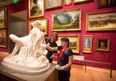 Esplorazione tattile di una scultura in un museo, da parte di una persona con disabilità