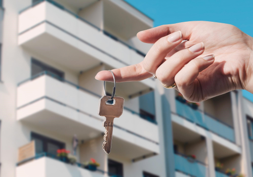 Mano con una chiave davanti a un condominio