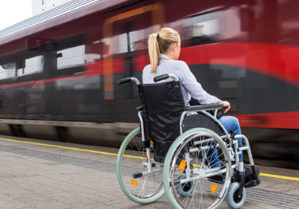 Giovane donna con disabilità davanti a un treno che passa