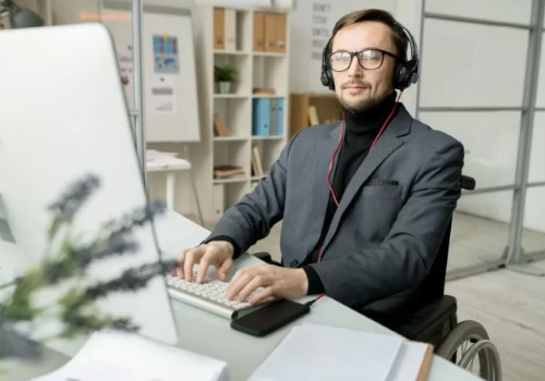 Persona con disabilità in carrozzina al computer
