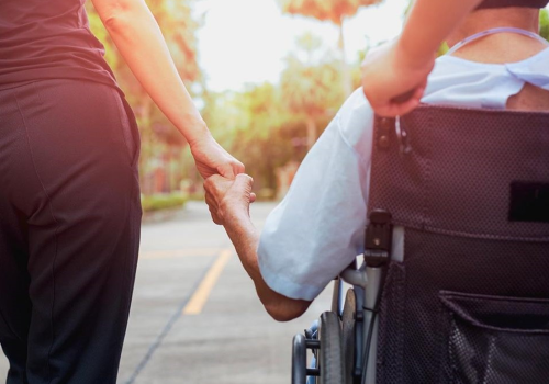 Foto di spalle di persona con disabilità e caregiver