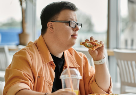 Persona con disabilità intellettiva che mangia una pizza