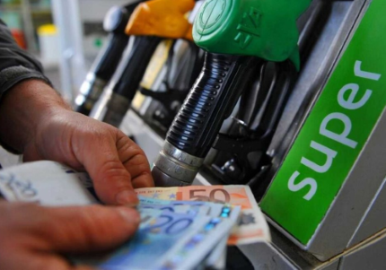 Mano con soldi davanti alle pompe di carburante