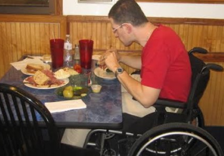 Persona con disabilità motoria che mangia al ristorante