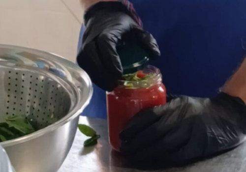 Mani di Fabrizio Landini che chiudono un barattolo di pomodoro