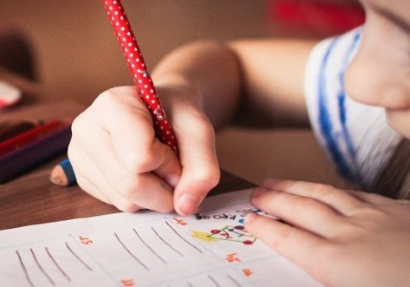 Particolare di bimba con disabilità che scrive con una matita colorata