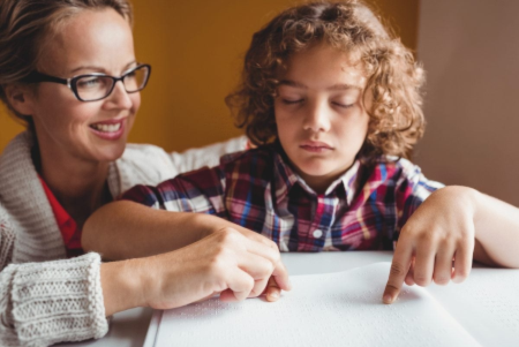 Un'assistente all'autonomia e alla comunicazione insieme a un bimbo con disabilità visiva