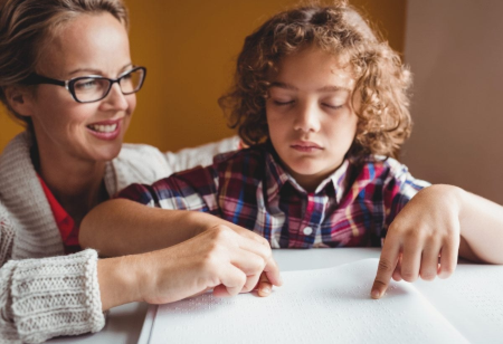Un'assistente all'autonomia e alla comunicazione insieme a un bimbo con disabilità visiva