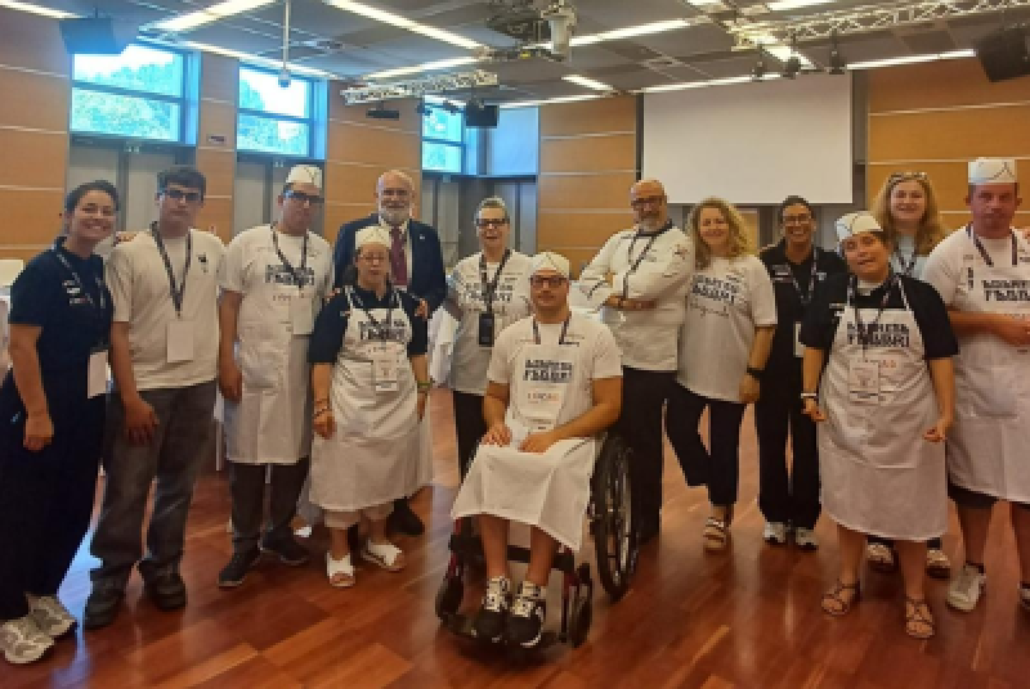 Il team di "Frolleria ANFFAS Mirandola" a "ExpoAid 2026", con Carlotta Fabbri, quinta generazione di Fabbri 1905 (prima a sinistra), Roberto Speziale, ppresidente nazionale dell'ANFFAS (quarto a sinistra, dietro), il pasticciere formatore Domenico Costanza (sesto da sinistra, dietro) e Marzia Manderioli, presidente dell'ANFFAS di Mirandola (ottava da sinistra, dietro)