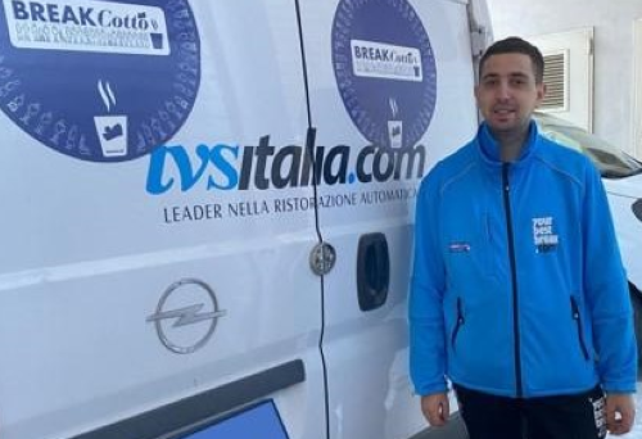 Giulio al lavoro, vicino a un furgone dell’IVS Italia, in cui si vede il logo di "BREAKCotto"