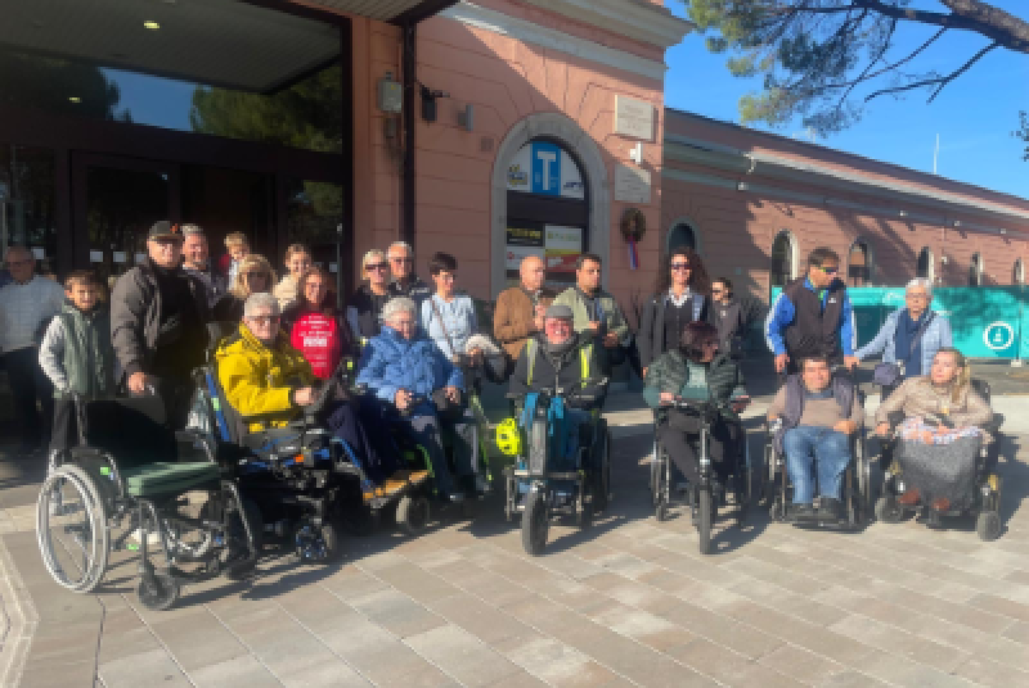 Foto di gruppo per una serie di partecipanti alla "Passeggiata inclusiva" di Gorizia, davanti alla stazione ferroviaria