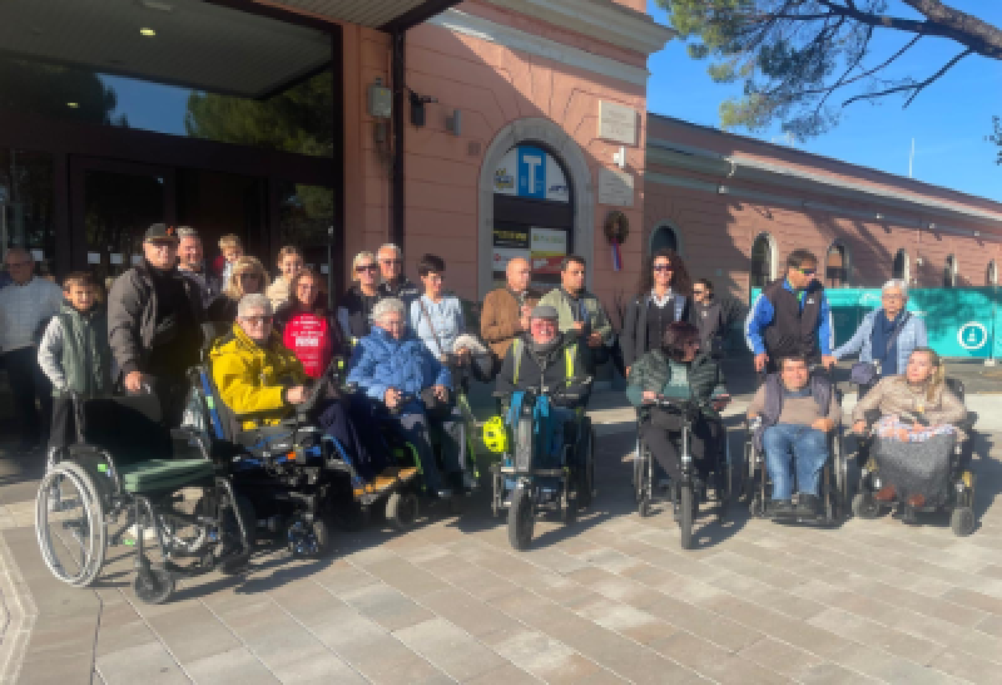 Foto di gruppo per una serie di partecipanti alla "Passeggiata inclusiva" di Gorizia, davanti alla stazione ferroviaria