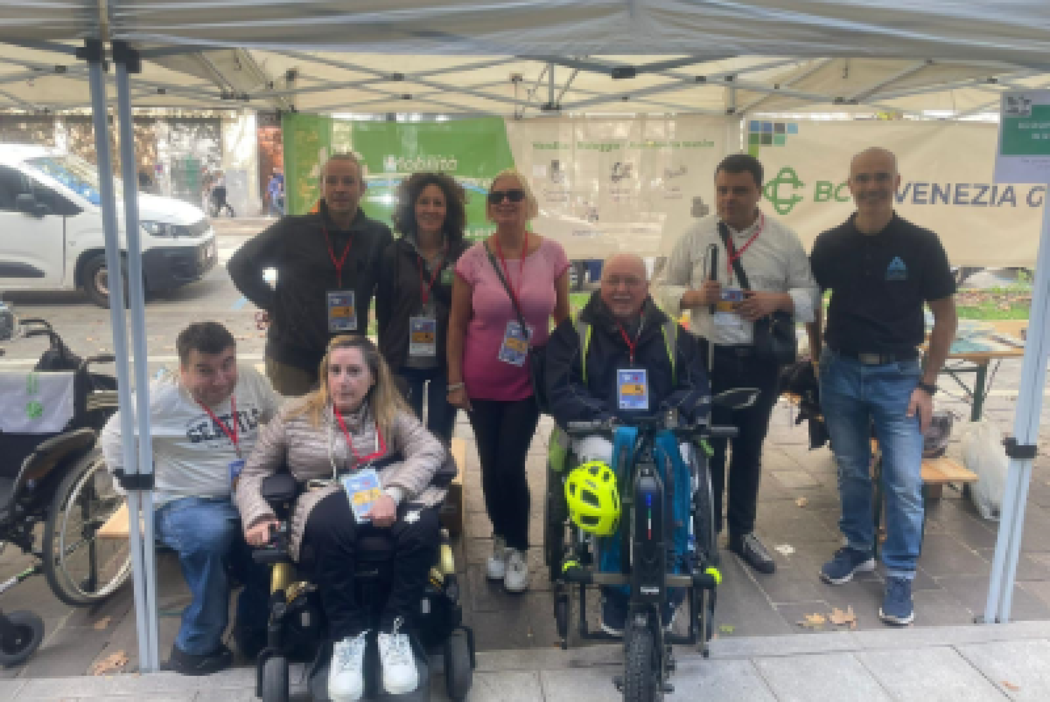 In primo piano, da destra, Giampiero Licinio, presidente della FISH Friuli Venezia Giulia, Alessandra Ferletti, presidente della UILDM di Gorizia e Massimiliano Mauri, altro componente di quest'ultima Associazione, davanti ad alcuni volontari presenti a "Gusti di Frontiera 2025"