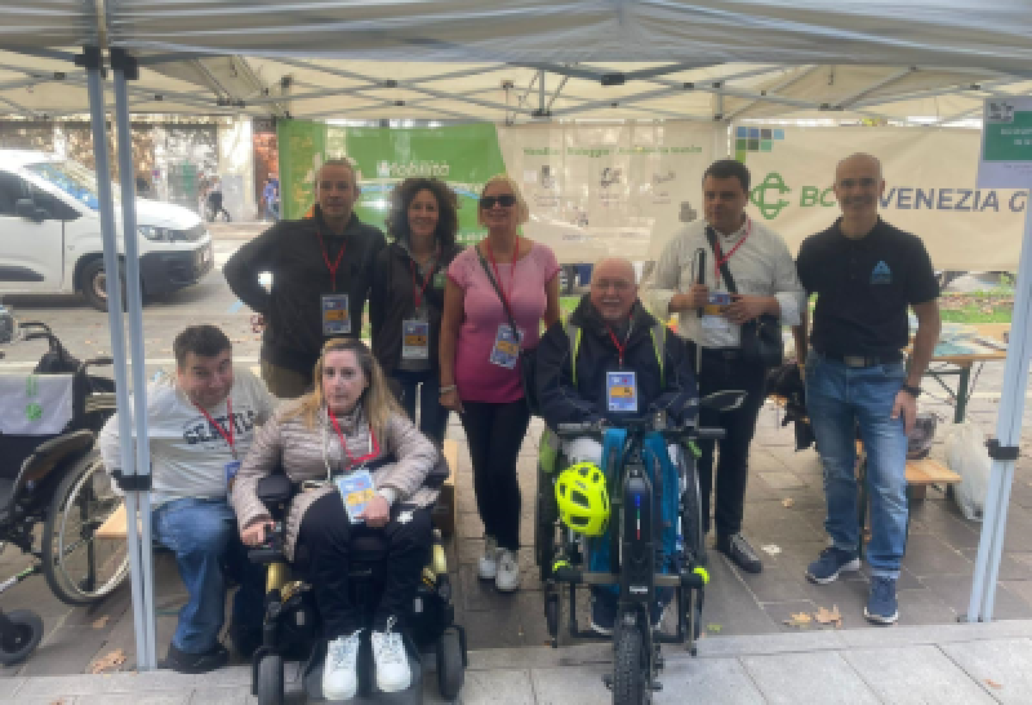 In primo piano, da destra, Giampiero Licinio, presidente della FISH Friuli Venezia Giulia, Alessandra Ferletti, presidente della UILDM di Gorizia e Massimiliano Mauri, altro componente di quest'ultima Associazione, davanti ad alcuni volontari presenti a "Gusti di Frontiera 2025"