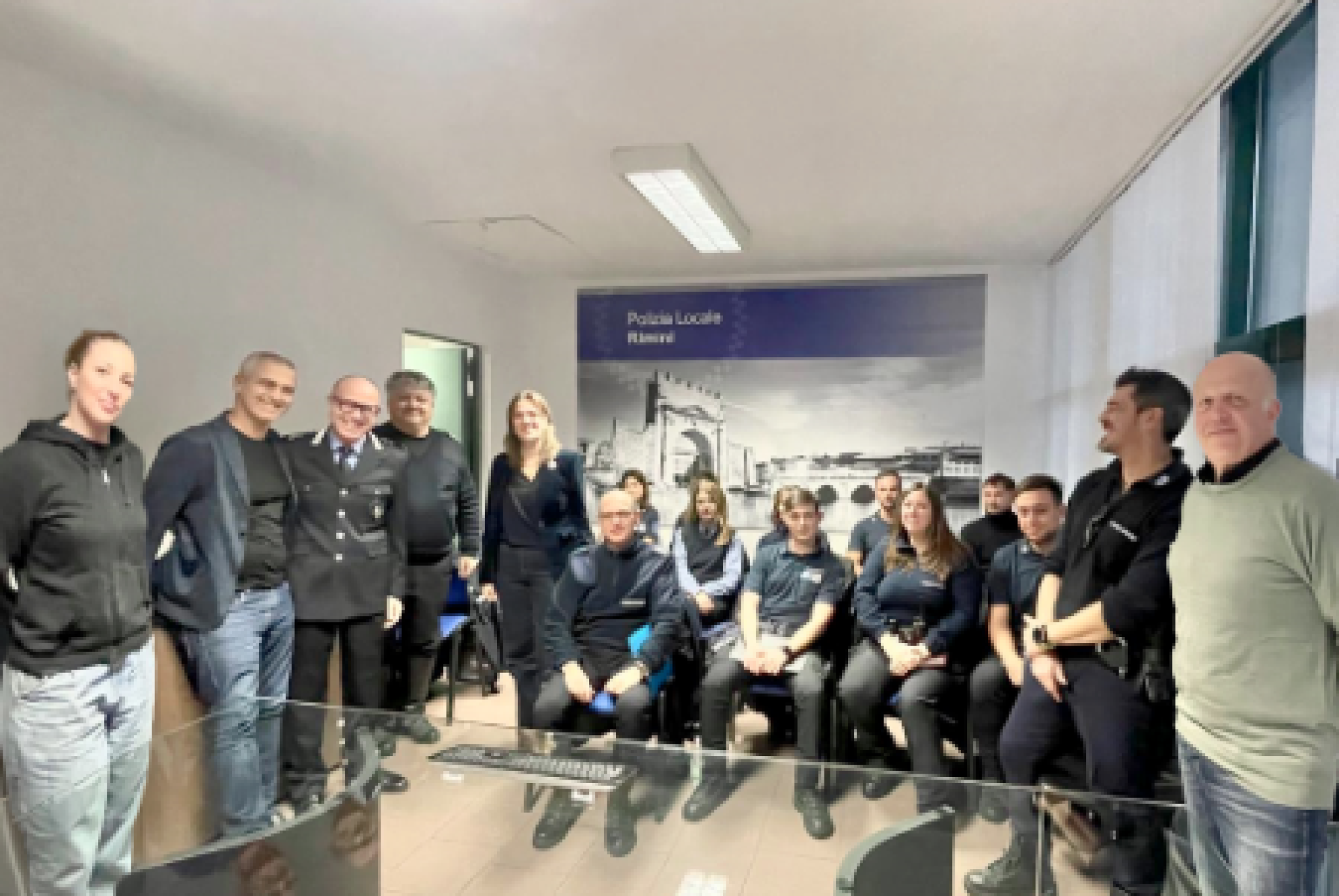 Un gruppo di agenti della Polizia Locale di Rimini con Alessandra Urbinati, presidente dell'Associazione Rimini Autismo, il sindaco della città Jamil Sadegholvaad, il comandante della Polizia Locale Andrea Rossi e altri genitori di Rimini Autismo